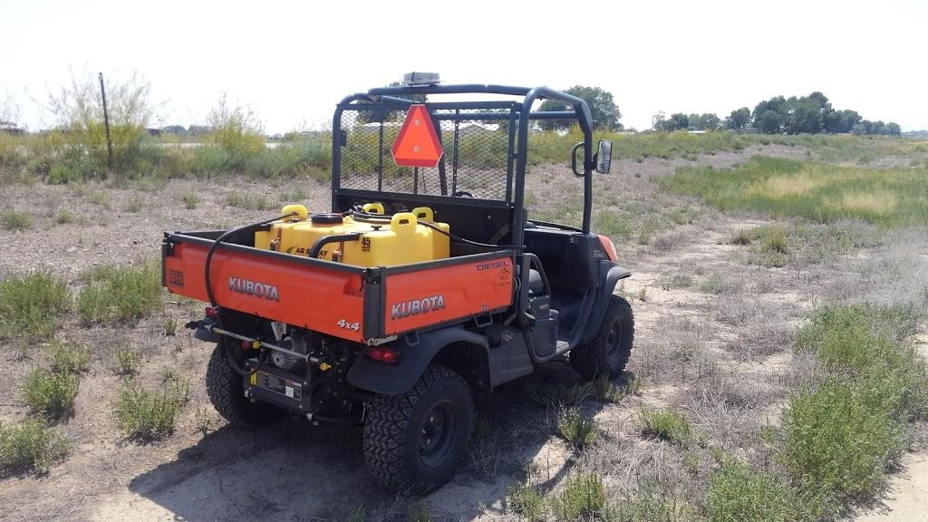 2019 Kubota UTV with a spray tank in the back in an open field with trees, bare ground, and a combination of native and invasive species