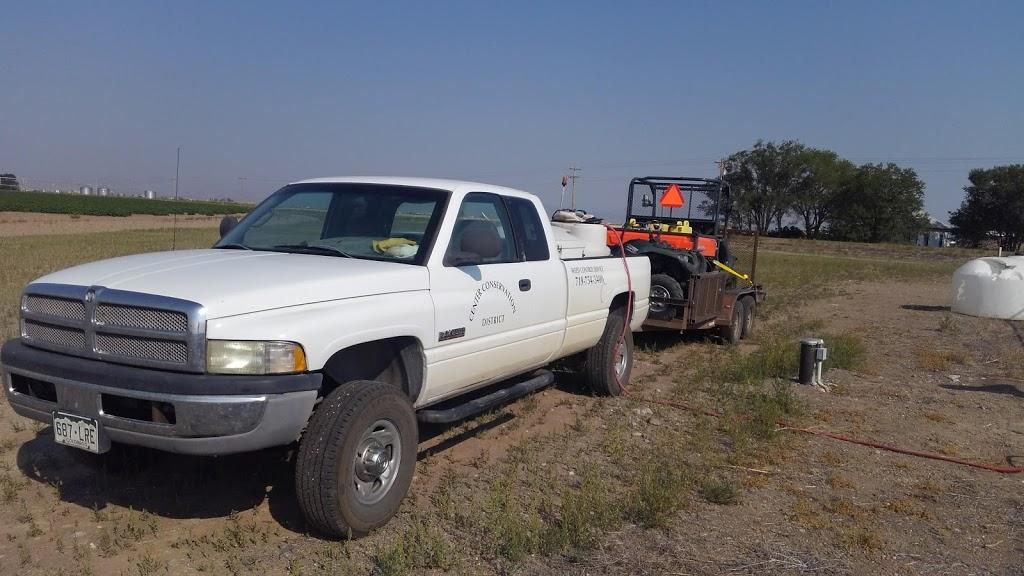 A 2013 Ram truck with the Center Conservation District logo on the driver's side door and a spray tank in the bed. A trailer with the Kubota UTV is attached to the pickup.